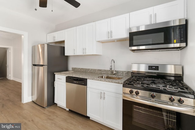 kitchen featuring sink, white cabinets, stainless steel appliances, light stone countertops, and light hardwood / wood-style flooring