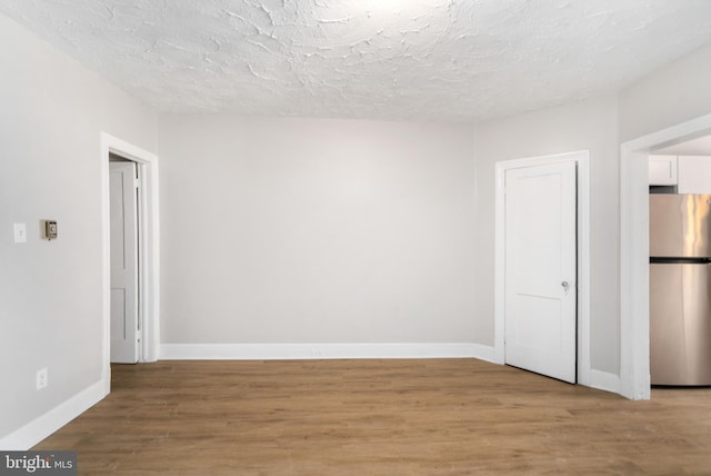 spare room with a textured ceiling and light wood-type flooring