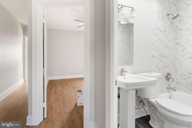 bathroom featuring hardwood / wood-style flooring, tiled shower / bath combo, and toilet