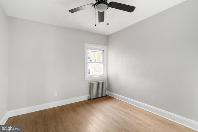 empty room featuring radiator heating unit and light hardwood / wood-style flooring