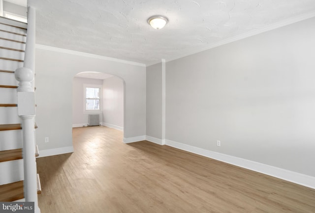 empty room featuring ornamental molding, light hardwood / wood-style floors, and a textured ceiling