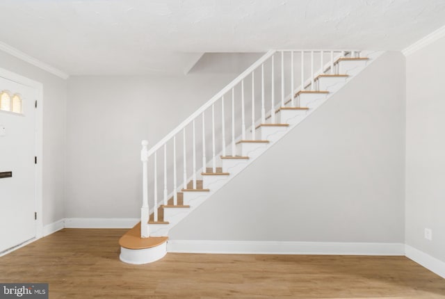 stairway with crown molding and hardwood / wood-style floors