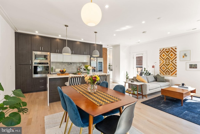 dining space with crown molding and light hardwood / wood-style floors