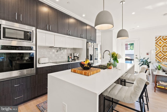 kitchen featuring decorative light fixtures, a kitchen island with sink, white cabinetry, and appliances with stainless steel finishes