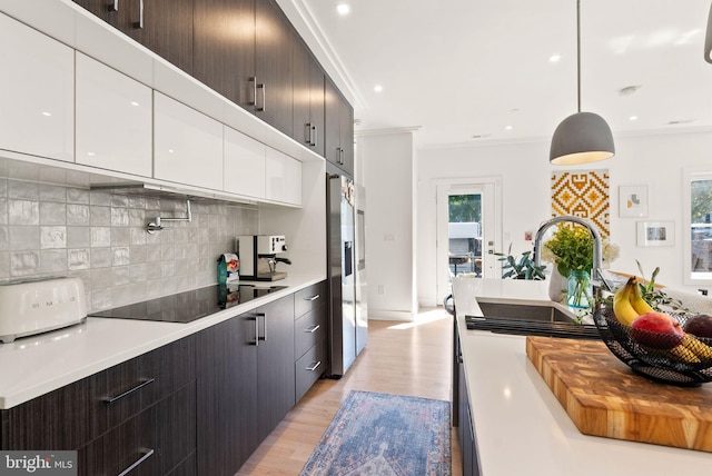 kitchen with white cabinetry, decorative backsplash, light wood-type flooring, decorative light fixtures, and ornamental molding