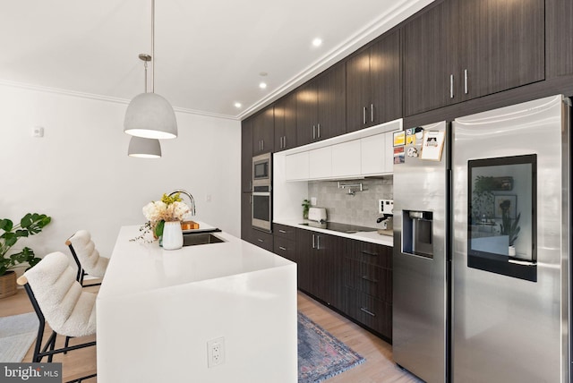 kitchen with crown molding, appliances with stainless steel finishes, sink, decorative light fixtures, and a breakfast bar area