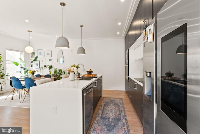 kitchen featuring sink, a center island with sink, hardwood / wood-style floors, and hanging light fixtures