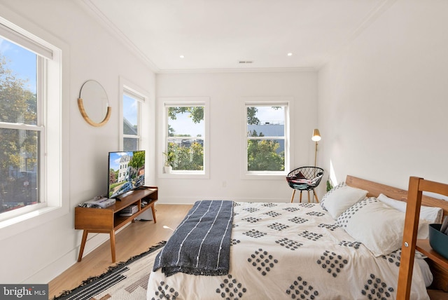 bedroom featuring hardwood / wood-style flooring, crown molding, and multiple windows