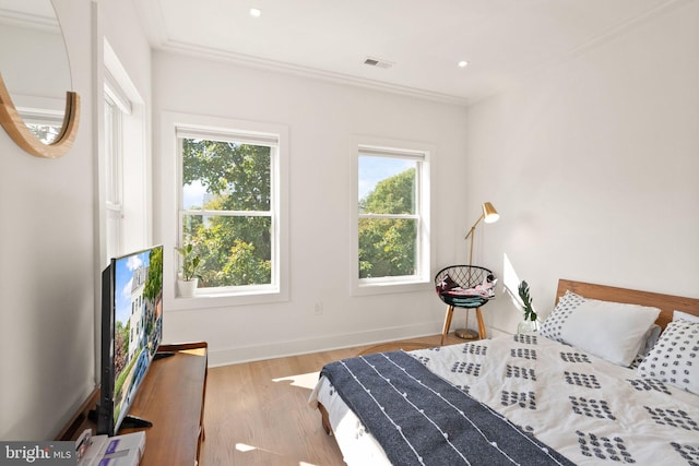 bedroom with multiple windows, crown molding, and hardwood / wood-style floors