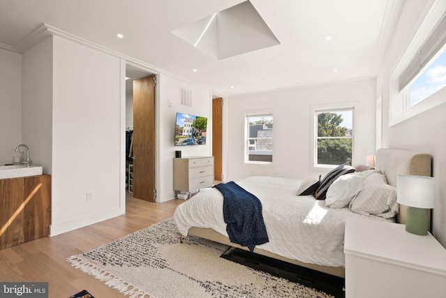 bedroom with sink, ornamental molding, and light hardwood / wood-style floors