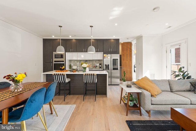 living room featuring sink, light hardwood / wood-style floors, and ornamental molding