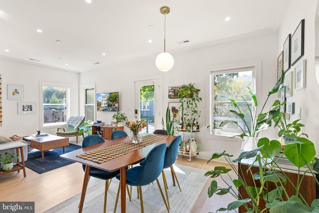 dining area with crown molding, light wood-type flooring, and a wealth of natural light