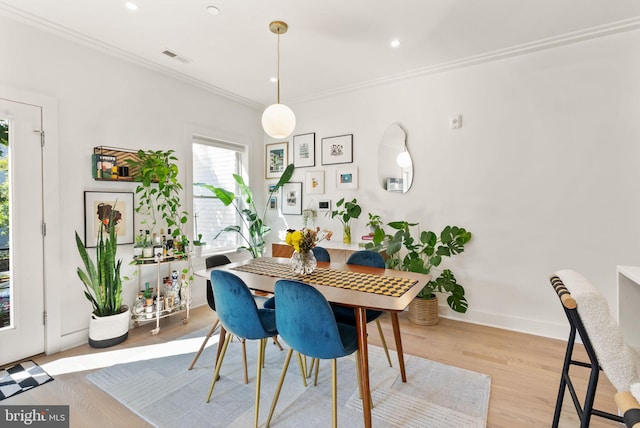 dining room with light wood-type flooring and crown molding