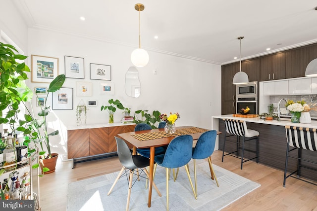 dining area featuring crown molding and light hardwood / wood-style flooring