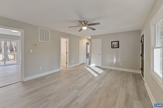 empty room featuring ceiling fan, a wealth of natural light, and light hardwood / wood-style flooring