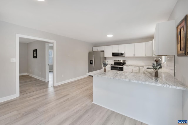 kitchen with light stone countertops, white cabinets, sink, kitchen peninsula, and stainless steel appliances