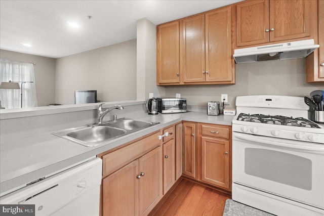 kitchen featuring white appliances, kitchen peninsula, sink, and light wood-type flooring