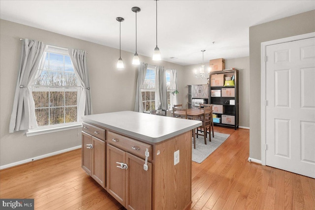 kitchen featuring a center island, a notable chandelier, light hardwood / wood-style floors, and decorative light fixtures