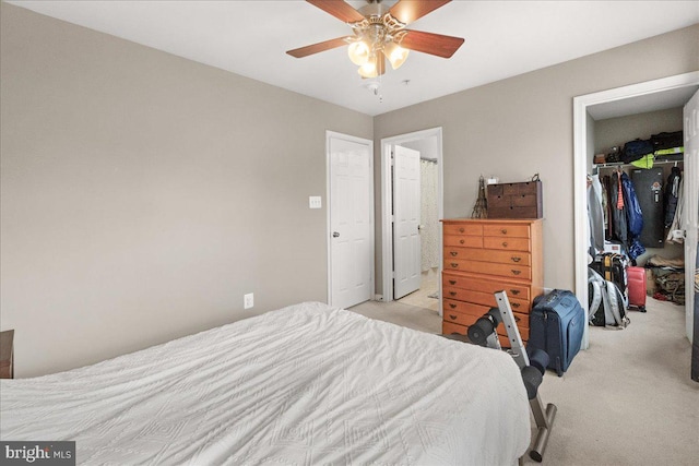 carpeted bedroom featuring connected bathroom, a spacious closet, a closet, and ceiling fan