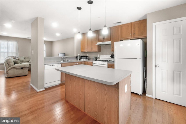 kitchen featuring a kitchen island, sink, hanging light fixtures, white appliances, and light hardwood / wood-style flooring