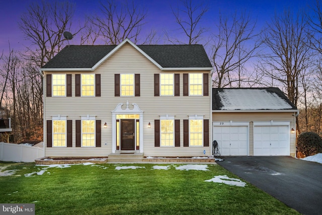 colonial home featuring a garage and a lawn