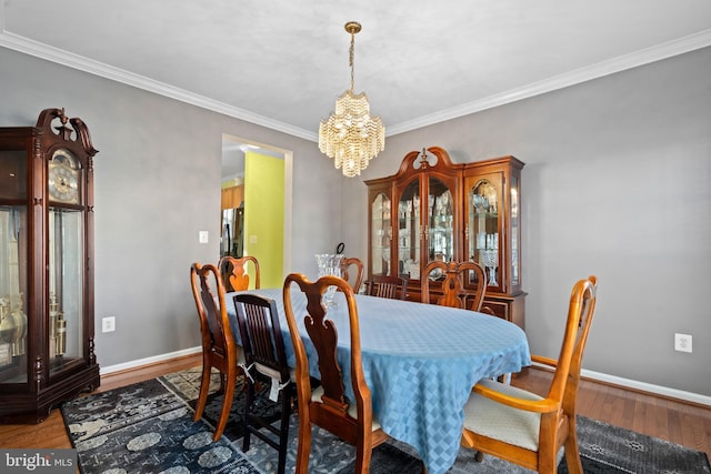 dining area with hardwood / wood-style flooring, crown molding, and an inviting chandelier