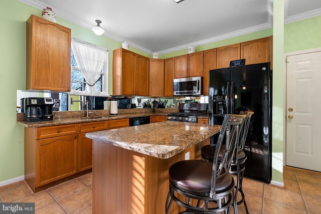 kitchen with sink, a breakfast bar area, stone counters, a center island, and black appliances