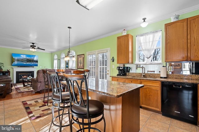 kitchen with sink, decorative light fixtures, a center island, black dishwasher, and stone counters