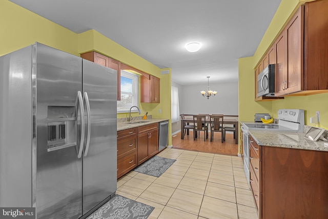 kitchen featuring hanging light fixtures, appliances with stainless steel finishes, sink, light tile patterned floors, and light stone counters