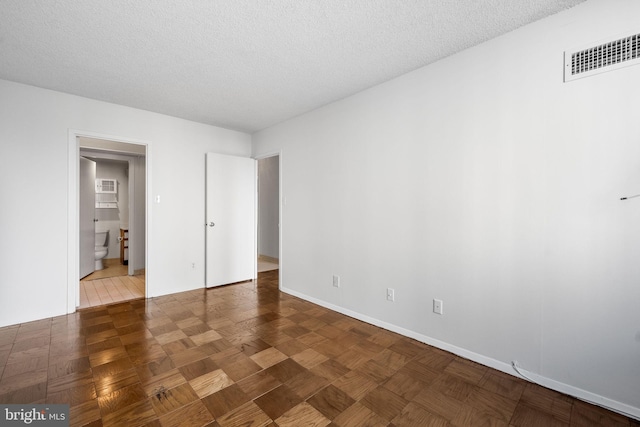 unfurnished room with dark parquet flooring and a textured ceiling