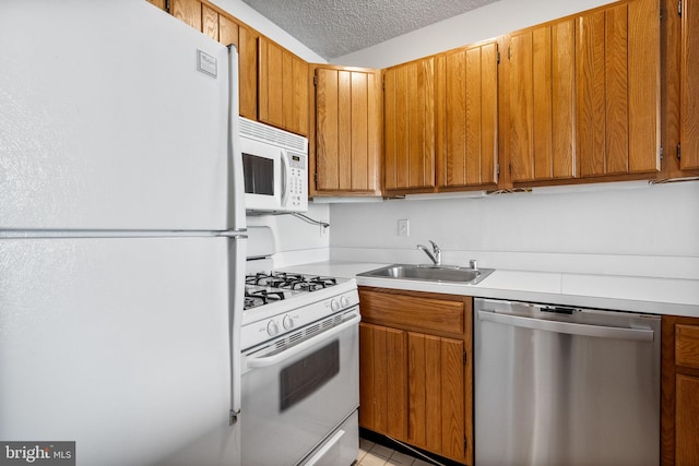 kitchen featuring white appliances, sink, and a textured ceiling