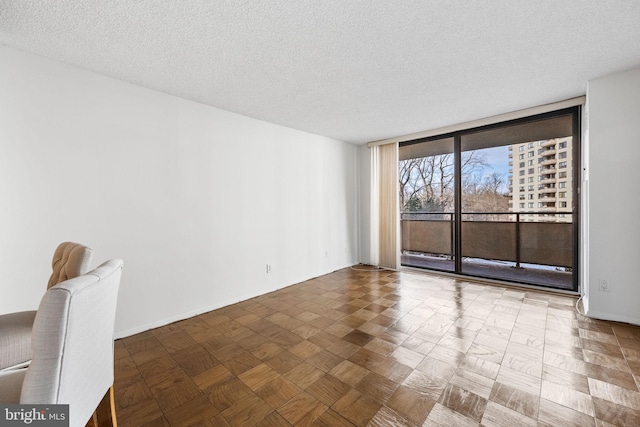 unfurnished room featuring a textured ceiling and a wall of windows