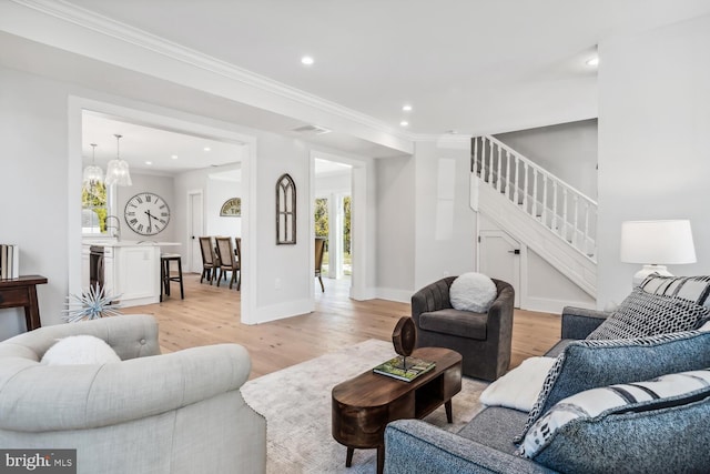 living room with crown molding, a notable chandelier, and light hardwood / wood-style flooring