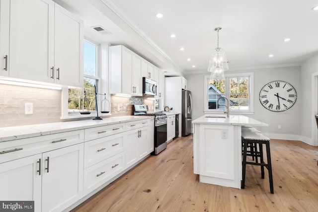 kitchen with stainless steel appliances, white cabinetry, a kitchen island, and sink