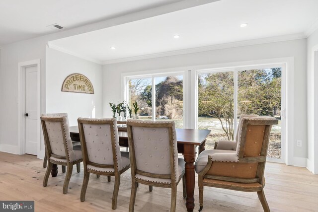 dining area with ornamental molding and light hardwood / wood-style floors