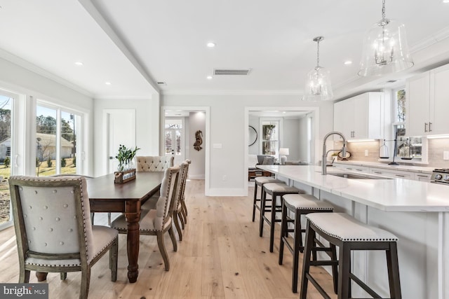 dining room featuring ornamental molding, sink, and light wood-type flooring