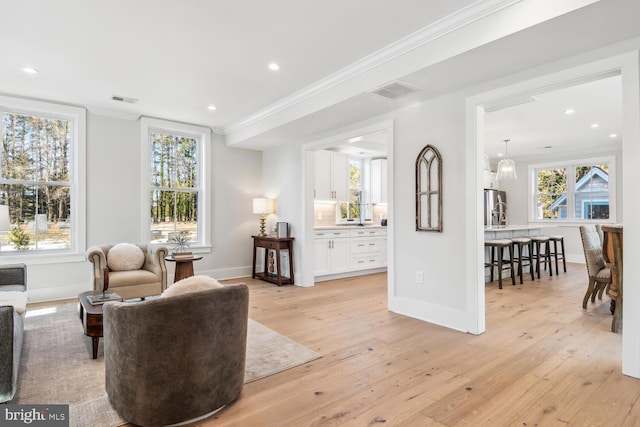 living area with crown molding and light hardwood / wood-style flooring