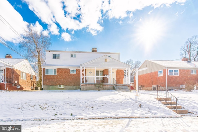 snow covered rear of property featuring a porch