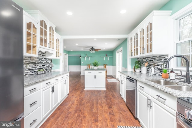 kitchen with appliances with stainless steel finishes, dark hardwood / wood-style floors, sink, white cabinets, and light stone counters