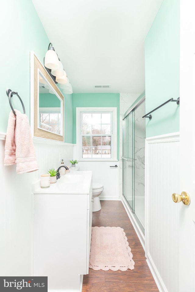 bathroom with vanity, toilet, a shower with shower door, and wood-type flooring