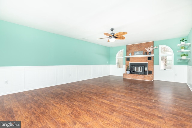 unfurnished living room featuring a fireplace, dark wood-type flooring, and ceiling fan