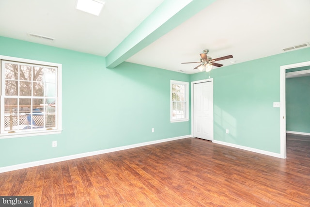 empty room featuring beamed ceiling, ceiling fan, and dark wood-type flooring