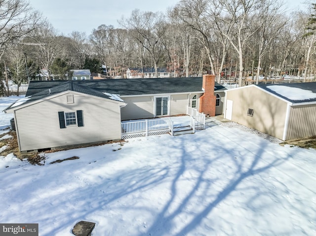 snow covered rear of property with a wooden deck