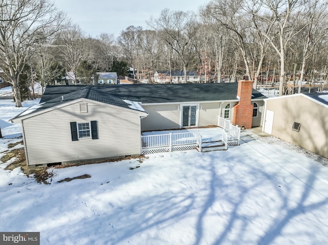 snow covered back of property with a wooden deck