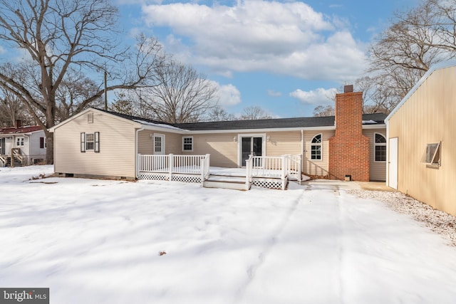 snow covered back of property featuring a wooden deck