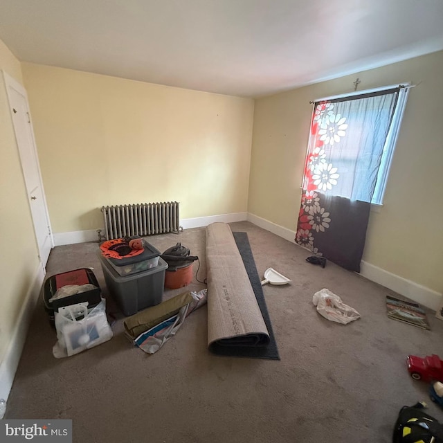 spare room with baseboards, carpet floors, and radiator