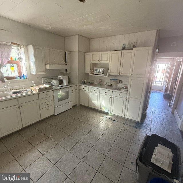 kitchen featuring white electric range, a sink, white cabinets, light countertops, and wall chimney range hood