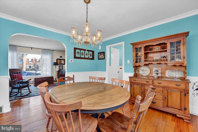 dining space featuring light hardwood / wood-style floors, ornamental molding, and an inviting chandelier