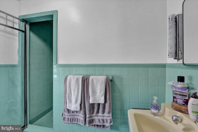 bathroom featuring sink, a tile shower, and tile walls