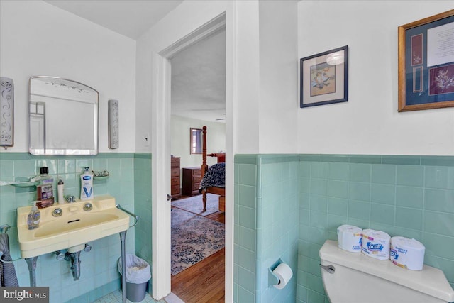 bathroom featuring hardwood / wood-style floors, toilet, and tile walls